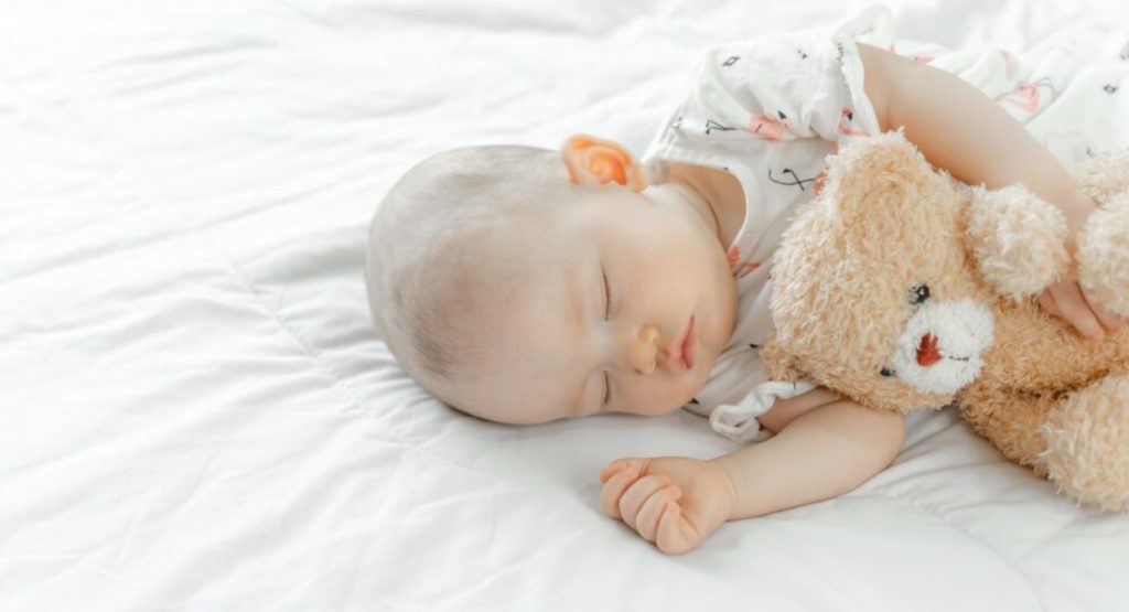 Bébé qui dort avec un nounours