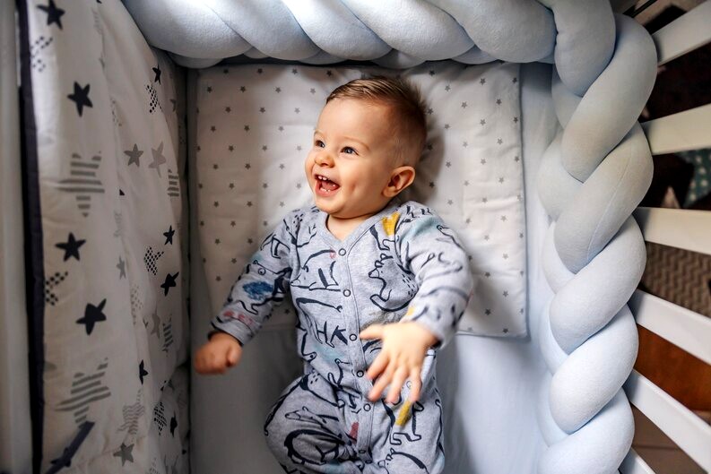Bébé riant dans un berceau entouré d'une tresse de lit